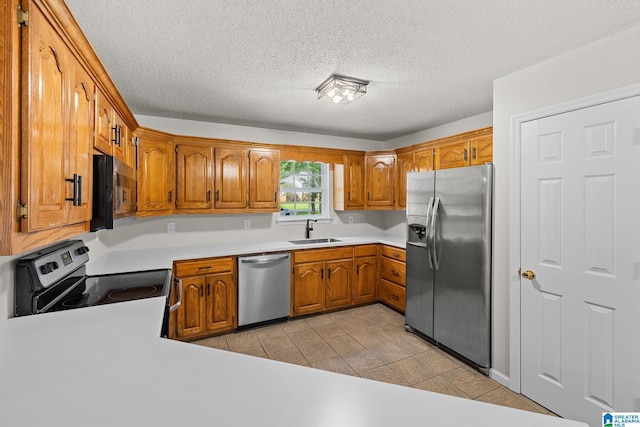 6415 Mays Bend Rd, Pell City, AL 35128 - kitchen featuring appliances with stainless steel finishes, a sink, brown cabinetry, light countertops, and a textured ceiling