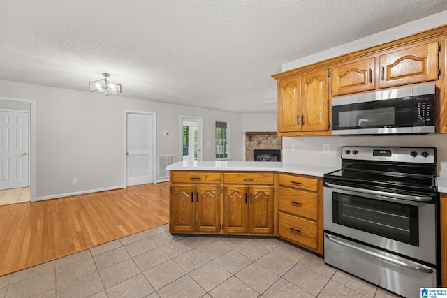 6415 Mays Bend Rd, Pell City, AL 35128 - kitchen with appliances with stainless steel finishes, a peninsula, light countertops, light tile patterned floors, and a textured ceiling