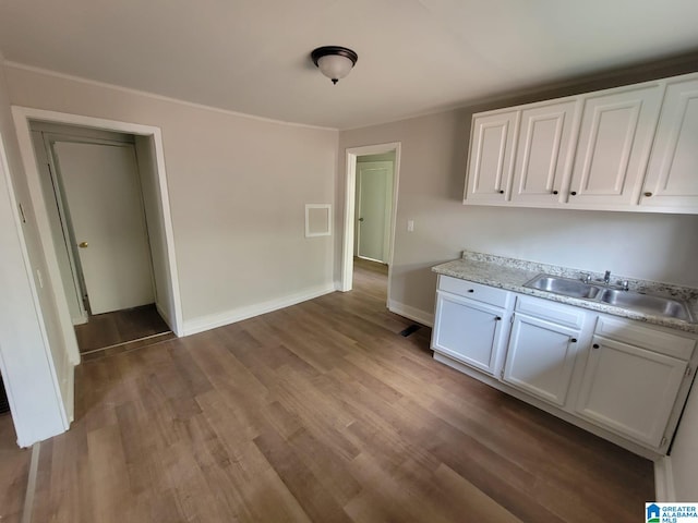 2308 Mayfield Ave, Birmingham, AL 35211 - kitchen featuring a sink, light countertops, white cabinets, wood finished floors, and baseboards