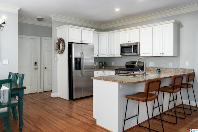 145 Lake Davidson Ln, Helena, AL 35080 - kitchen with appliances with stainless steel finishes, a peninsula, wood finished floors, a breakfast bar, and ornamental molding
