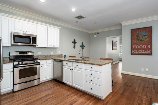 145 Lake Davidson Ln, Helena, AL 35080 - kitchen with appliances with stainless steel finishes, a peninsula, wood finished floors, crown molding, and light stone countertops