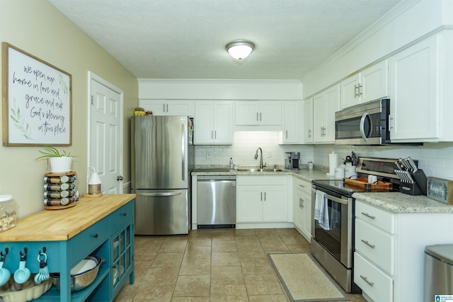 209 Meadowgreen Dr, Montevallo, AL 35115 - kitchen with stainless steel appliances, a sink, white cabinetry, backsplash, and ornamental molding