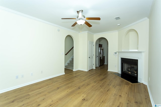 2449 Ridgemont Dr, Birmingham, AL 35244 - unfurnished living room featuring a ceiling fan, crown molding, a fireplace, arched walkways, and light wood-style flooring