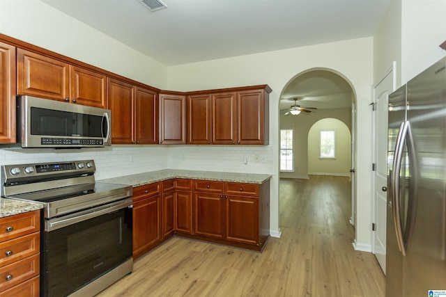 2449 Ridgemont Dr, Birmingham, AL 35244 - kitchen with appliances with stainless steel finishes, arched walkways, light wood-style floors, backsplash, and ceiling fan