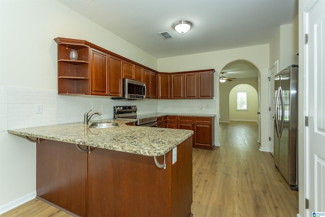 2449 Ridgemont Dr, Birmingham, AL 35244 - kitchen with appliances with stainless steel finishes, a sink, a peninsula, arched walkways, and light wood-style floors