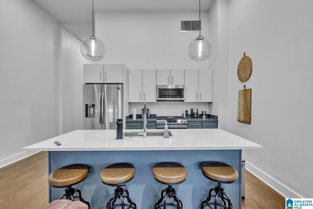 1801 2nd Ave N Unit 309, Birmingham, AL 35203 - kitchen featuring stainless steel appliances, a breakfast bar, baseboards, light wood-type flooring, and hanging light fixtures