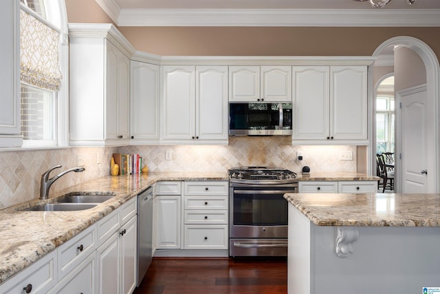 4025 Grove Park Cir, Birmingham, AL 35242 - kitchen featuring stainless steel appliances, a sink, arched walkways, crown molding, and white cabinets