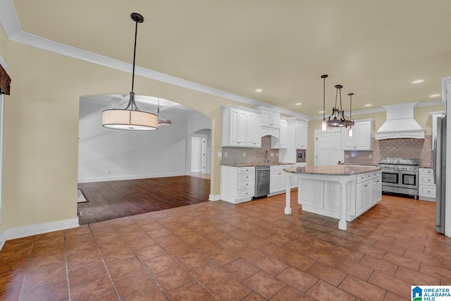 101 N Lake Dr, Hoover, AL 35242 - kitchen featuring stainless steel appliances, custom exhaust hood, backsplash, arched walkways, and white cabinets