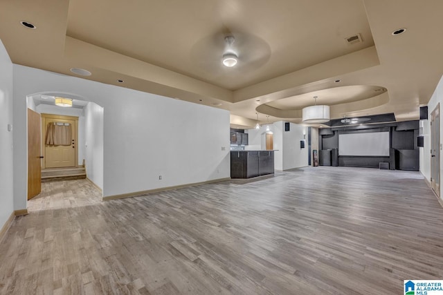 101 N Lake Dr, Hoover, AL 35242 - unfurnished living room featuring a raised ceiling, wood finished floors, arched walkways, and ceiling fan