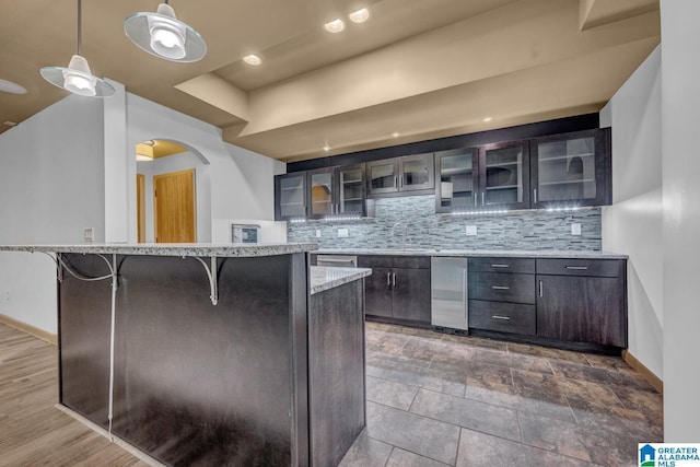 101 N Lake Dr, Hoover, AL 35242 - kitchen featuring arched walkways, a breakfast bar, tasteful backsplash, and glass insert cabinets