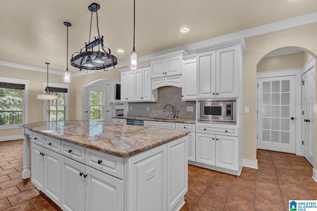 101 N Lake Dr, Hoover, AL 35242 - kitchen with arched walkways, recessed lighting, a kitchen island, stainless steel microwave, and tasteful backsplash