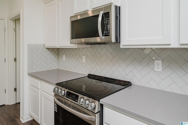 1063 Timberline Rdg, Calera, AL 35040 - kitchen featuring appliances with stainless steel finishes, light countertops, white cabinetry, tasteful backsplash, and dark wood-type flooring