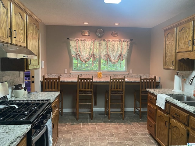 13634 Lisa Dr, Lake View, AL 35111 - kitchen with gas stove, under cabinet range hood, a sink, light stone counters, and recessed lighting