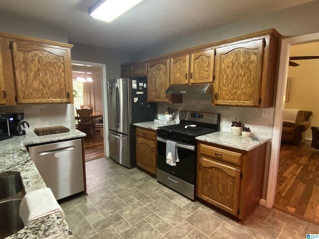 13634 Lisa Dr, Lake View, AL 35111 - kitchen with stainless steel appliances, under cabinet range hood, light stone countertops, and brown cabinetry