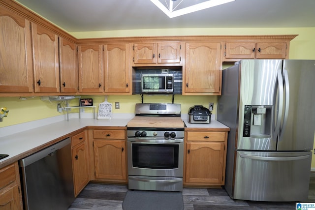 13339 Sylvia Dr, Lake View, AL 35111 - kitchen with appliances with stainless steel finishes, dark wood finished floors, light countertops, and brown cabinetry