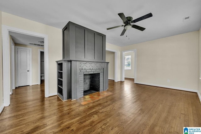 741 Center Pl SW, Birmingham, AL 35211 - unfurnished living room featuring wood finished floors, a ceiling fan, and a brick fireplace
