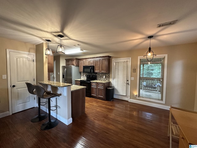 21131 Delmar Dr, Lake View, AL 35111 - kitchen featuring black appliances, a peninsula, dark wood-style flooring, a breakfast bar, and light stone countertops