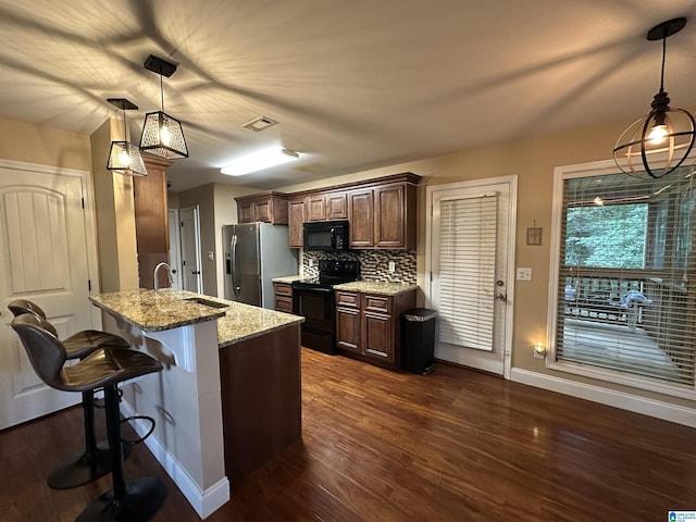 21131 Delmar Dr, Lake View, AL 35111 - kitchen featuring black appliances, a breakfast bar area, a peninsula, dark wood-type flooring, and light stone countertops