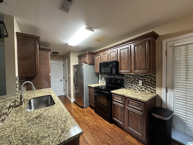 21131 Delmar Dr, Lake View, AL 35111 - kitchen featuring black appliances, wood finished floors, decorative backsplash, dark brown cabinets, and light stone countertops
