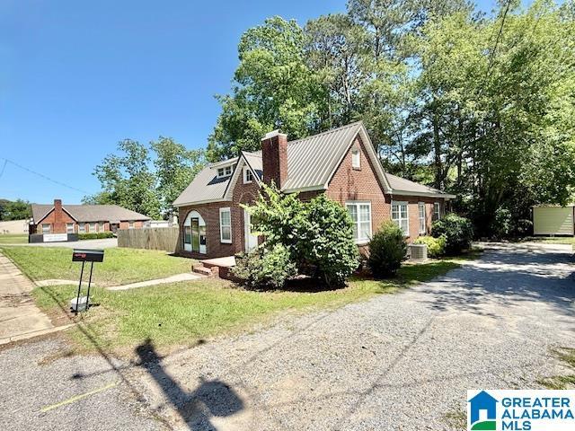 1005 4th Ave N, Clanton, AL 35045 - view of home's exterior featuring a chimney, driveway, and brick siding