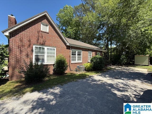 1005 4th Ave N, Clanton, AL 35045 - view of property exterior with a chimney, brick siding, asphalt driveway, and central AC