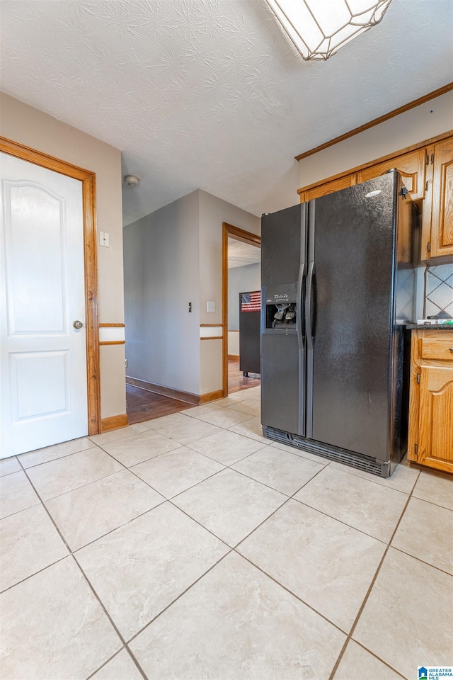 1709 Round Hill Rd, Weaver, AL 36277 - kitchen with black fridge with ice dispenser, light tile patterned flooring, brown cabinetry, and a textured ceiling