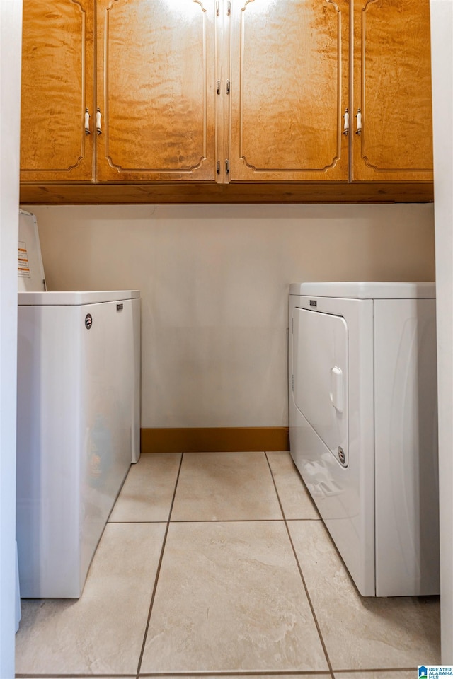 1709 Round Hill Rd, Weaver, AL 36277 - washroom with washing machine and clothes dryer, cabinet space, light tile patterned floors, and baseboards