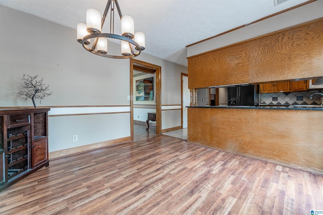 1709 Round Hill Rd, Weaver, AL 36277 - kitchen with a chandelier, brown cabinetry, dark countertops, and light wood-style flooring