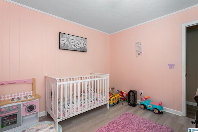 4507 Charles Ave, Anniston, AL 36206 - bedroom with wood finished floors, ornamental molding, a crib, and baseboards