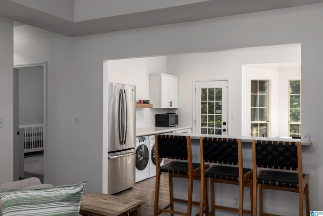 5883 William O Ln, Gardendale, AL 35071 - kitchen featuring appliances with stainless steel finishes, light countertops, white cabinets, wood finished floors, and washing machine and clothes dryer