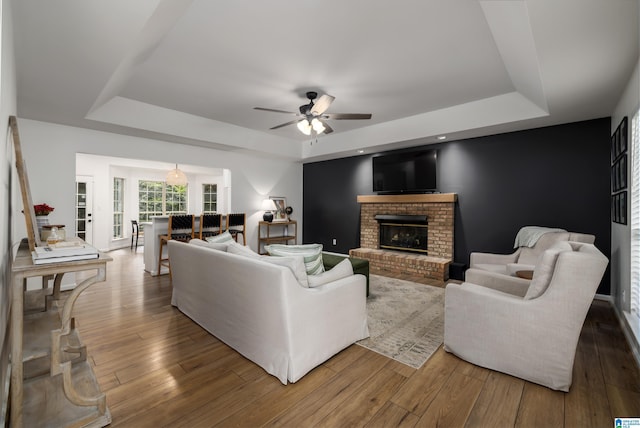 5883 William O Ln, Gardendale, AL 35071 - living room featuring a raised ceiling, a brick fireplace, a ceiling fan, and wood finished floors