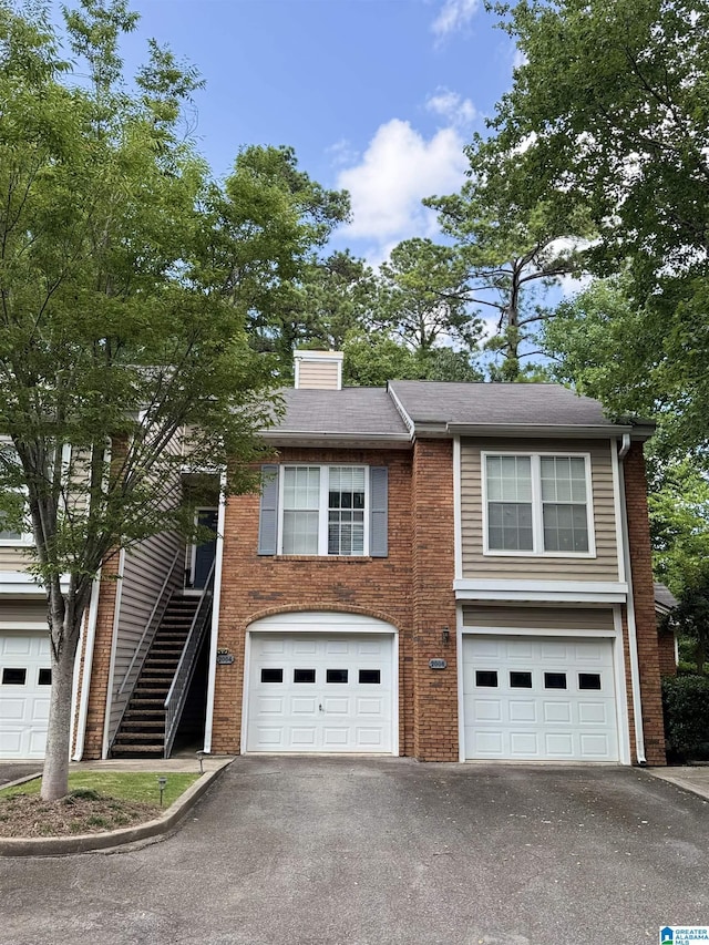 2004 Waterford Pl Unit 2004, Hoover, AL 35244 - view of front of home with driveway, an attached garage, brick siding, a chimney, and stairway