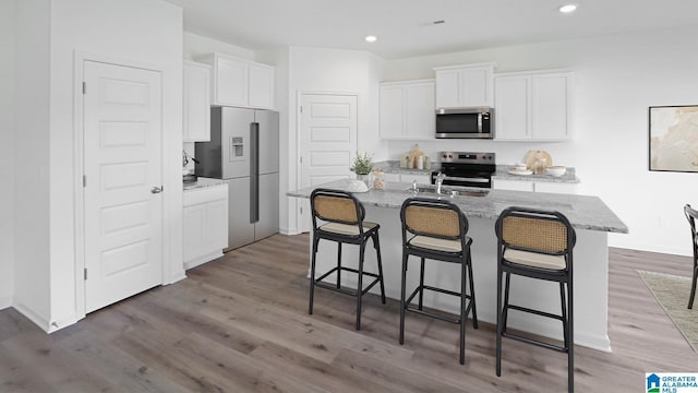 2008 Eaton Pl, Chelsea, AL 35043 - kitchen featuring appliances with stainless steel finishes, white cabinetry, an island with sink, light wood-style flooring, and recessed lighting