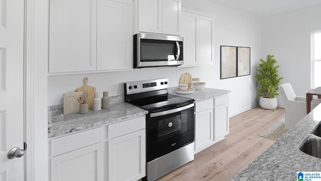 2008 Eaton Pl, Chelsea, AL 35043 - kitchen with stainless steel appliances, white cabinetry, light wood-style floors, light stone countertops, and baseboards