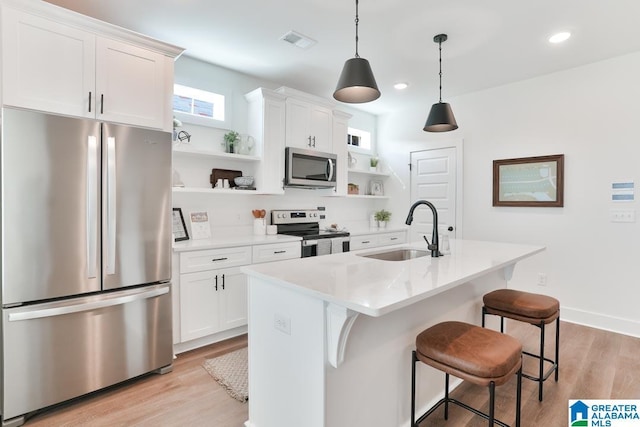 157 Shiloh Creek Dr, Calera, AL 35040 - kitchen featuring appliances with stainless steel finishes, open shelves, a sink, light wood-type flooring, and a kitchen bar