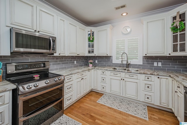 325 Driving Range Rd, Cropwell, AL 35054 - kitchen featuring appliances with stainless steel finishes, a sink, light wood-style flooring, tasteful backsplash, and ornamental molding