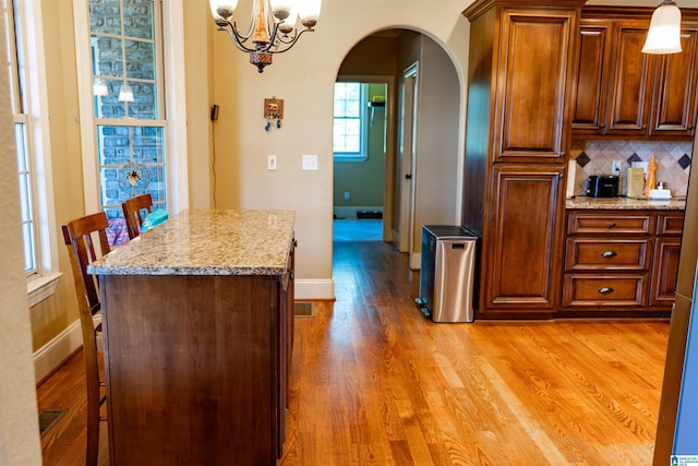 178 Jerry Marsh Rd, Locust Fork, AL 35097 - kitchen with arched walkways, a chandelier, tasteful backsplash, light wood-style flooring, and light stone countertops