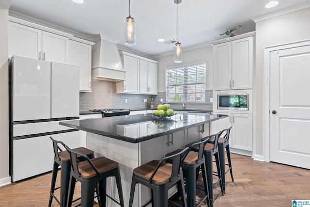 5182 Park Side Cir, Hoover, AL 35244 - kitchen with stainless steel appliances, premium range hood, crown molding, a breakfast bar, and backsplash