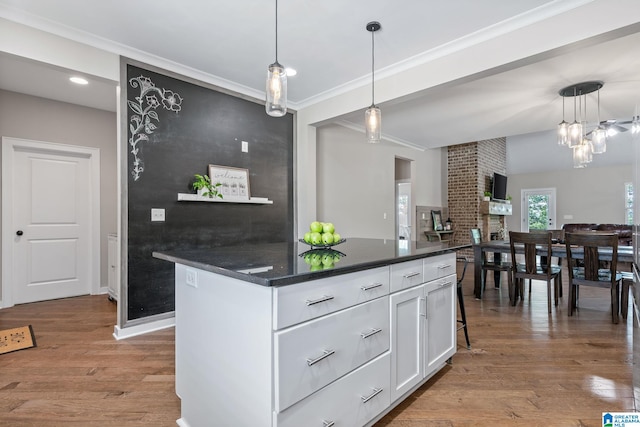 5182 Park Side Cir, Hoover, AL 35244 - kitchen with dark countertops, white cabinets, wood finished floors, hanging light fixtures, and crown molding