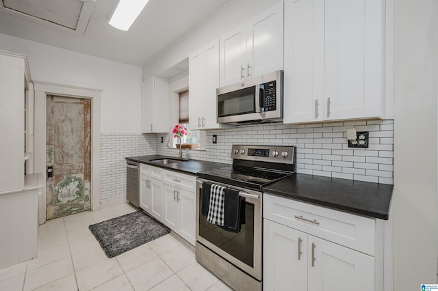 1319 17th St S, Birmingham, AL 35205 - kitchen with appliances with stainless steel finishes, dark countertops, light tile patterned floors, and white cabinets