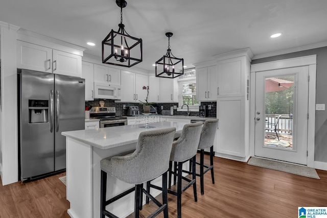 3303 Carousel Dr, Fultondale, AL 35068 - kitchen featuring appliances with stainless steel finishes, white cabinetry, a kitchen island, tasteful backsplash, and wood finished floors