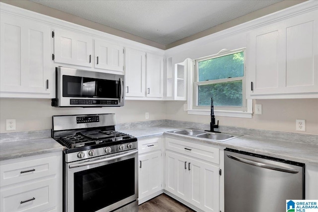2009 Palmer Ave, Leeds, AL 35094 - kitchen with stainless steel appliances, a sink, white cabinets, light countertops, and wood finished floors