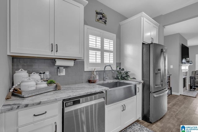 1515 Baxter Ave, Springville, AL 35146 - kitchen with appliances with stainless steel finishes, a sink, white cabinets, decorative backsplash, and wood finished floors