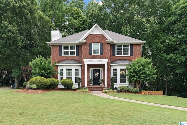1963 Russet Hill Ln, Hoover, AL 35244 - view of front of home with a chimney, brick siding, a front yard, and roof with shingles