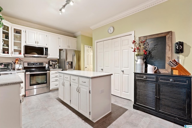 1963 Russet Hill Ln, Hoover, AL 35244 - kitchen featuring appliances with stainless steel finishes, tasteful backsplash, white cabinetry, ornamental molding, and glass insert cabinets