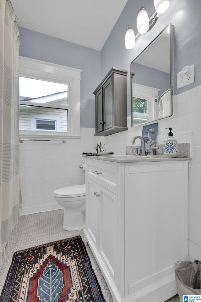 1138 14th Ave S, Birmingham, AL 35205 - bathroom with tile walls, toilet, vanity, healthy amount of natural light, and wainscoting
