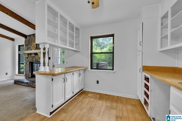 1117 Oak Creek Trl NE, Pinson, AL 35215 - kitchen featuring white cabinetry, open shelves, a stone fireplace, light wood-style flooring, and beamed ceiling