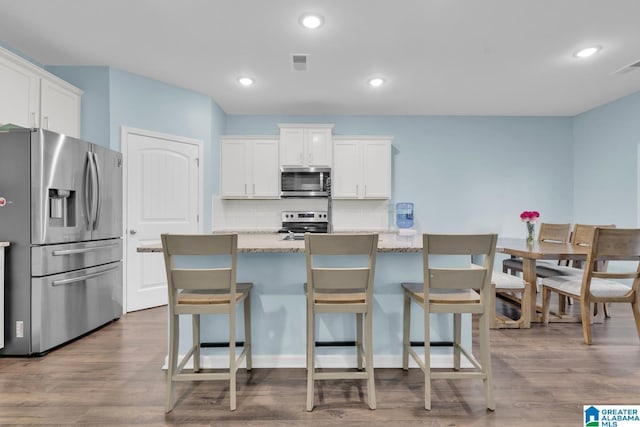 1009 Canvasback Way, Alabaster, AL 35007 - kitchen with appliances with stainless steel finishes, tasteful backsplash, white cabinets, a breakfast bar area, and recessed lighting