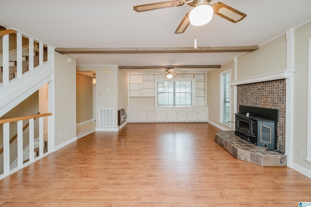 840 Black Acres Rd, Cropwell, AL 35054 - unfurnished living room with wood finished floors, ceiling fan, beam ceiling, stairway, and a wood stove