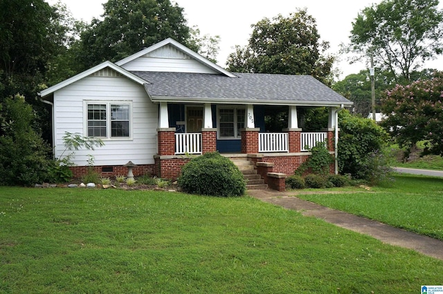 702 4th St SW, Childersburg, AL 35044 - view of front of house featuring a shingled roof, a porch, a front lawn, and brick siding